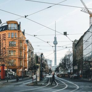 Marktforschungs aus Berlin: Ein typischer Straßenzug in Berlin-Mitte mit Altbauten, Straßenbahnschienen und dem Fernsehturm im Hintergrund.